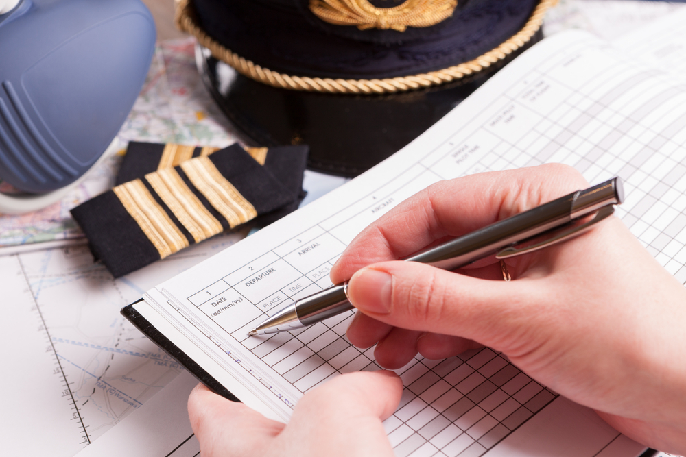 Pilot writing in a traditional paper logbook